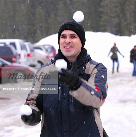 Happy man juggling snowballs in winter park