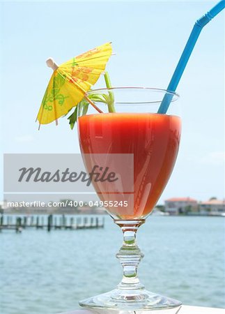 Bloody mary with yellow umbrella by the water