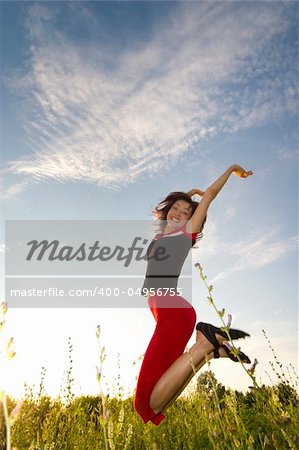 happy young beautiful girl jumping in the field