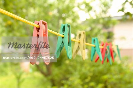 Some multi-coloured plastic clothespins on a yellow cord
