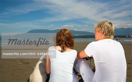 young couple on the beach with dog in vancouver - shot from behing
