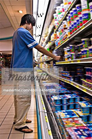 Young man shopping in a supermarket, fridge displays