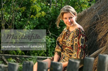 The beautiful rural girl sits on hay