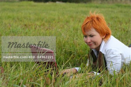 young woman with red notebook on grass