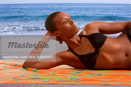 African-American female relaxing and taking sunbath by sea