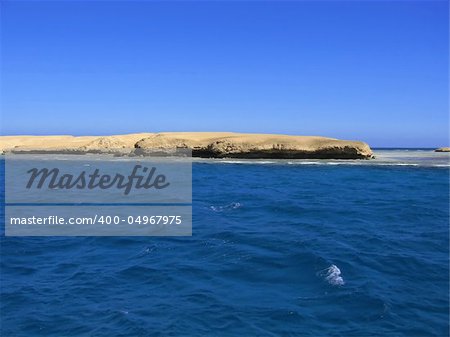The sandy island located at ocean, among small waves