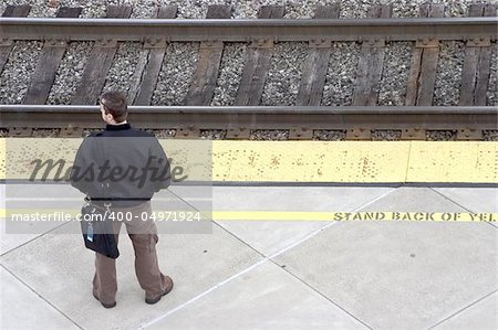 A man awaits the train for his morning commute to work.