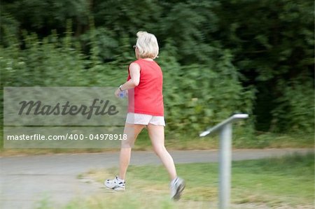 woman runs in the park, woman is in the focus, backgroung is blured