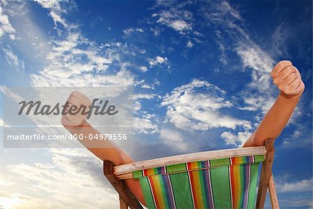 Woman stretching in deckchair with sunset sky behind her