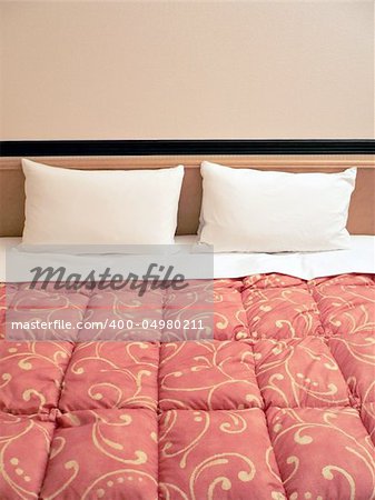 served bed with two pillows in hotel room