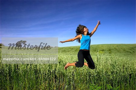 Young active woman jumping on a green field