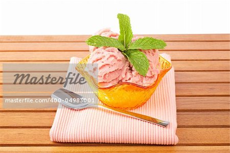 Delicious raspberries ice cream in glass bowl on wooden background. Shallow depth of field