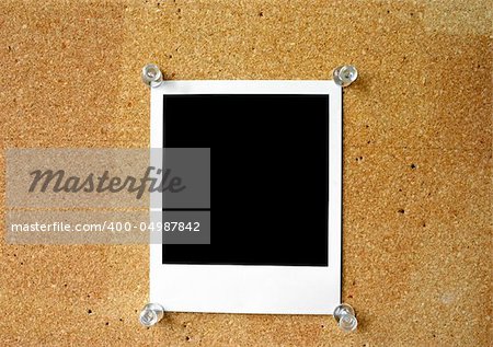 blank photo frame thumbtacked to cork board