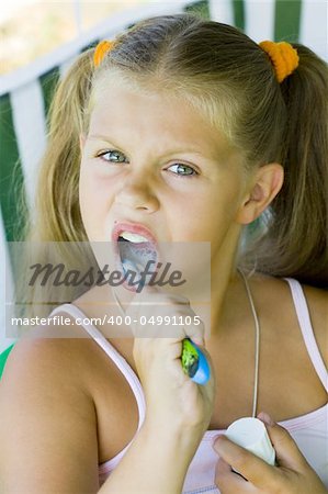 little blond girl cleaning teeth by toothbrush