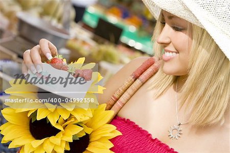 A beautiful young woman shopping for strawberries in a market