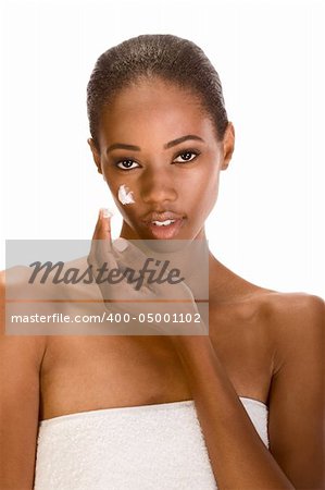 Beautiful young ethnic woman with Slicked Back Hair wrapped in white bath towel applying moisturizer on her face
