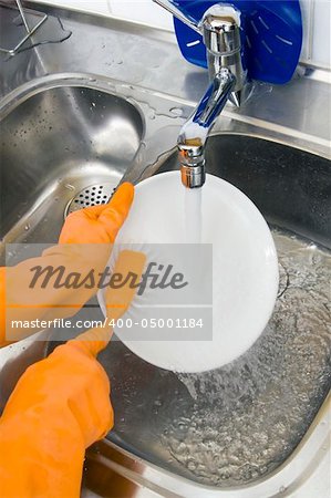 hands in gloves washing dishes at the kitchen