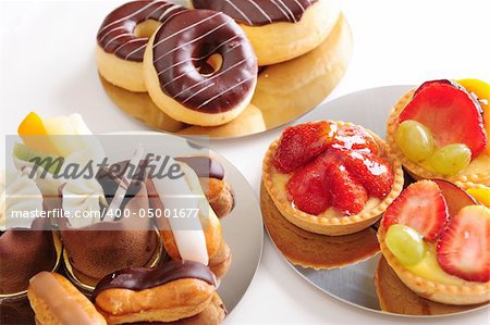 Delicious freshly baked pastries on shiny plates. White background, not isolated.