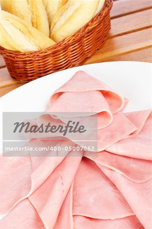 Slices of tasty ham on white dish and bread. Shallow depth of field