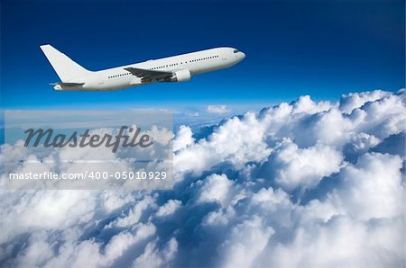Large airliner climbing along cloud top against a deep blue sky