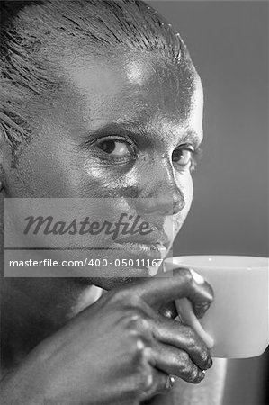 an attractive young girl covered with silver paint holding a coffee cup