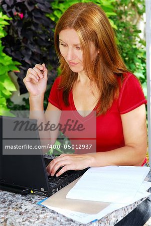 Happy mature woman working on a portable computer in her garden