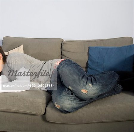 a teenage boy asleep and stretched out on sofa