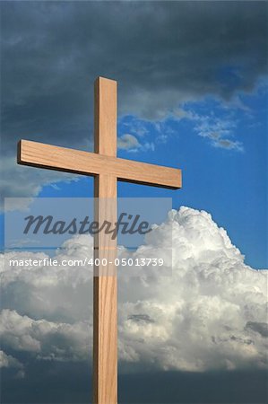 Wooden cross against a blue sky with storm clouds.