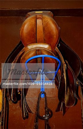 Two saddles on a rack in a tack room, horseback riding equipment