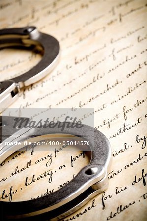 handcuffs closeup on United States Constitution with focus on Liberty