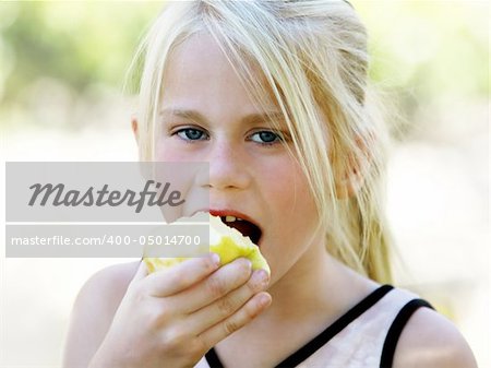 A funny blond girl eating an apple