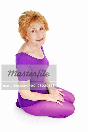 A beautiful seventy year old woman kneeling in her workout clothes.  White background.