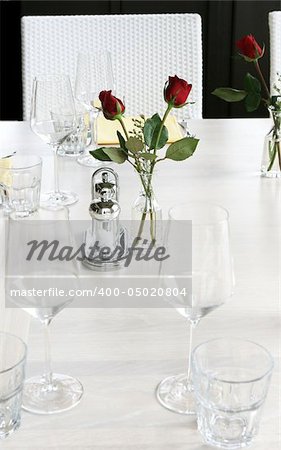 Elegant table setting with red roses and white linen.