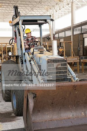 A man on a construction site driving a backhoe loader.