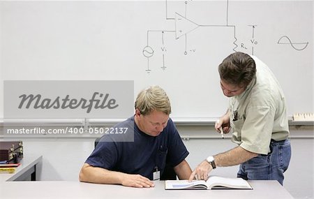 A middle aged adult education student getting help from his teacher.