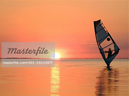 Silhouette of a windsurfer on waves of a gulf on a sunset 3