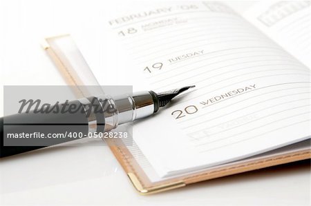 ink pen and brown calendar over white background