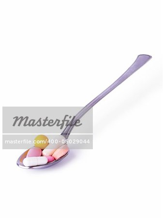 Yellow, white and pink colored pills in a spoon on a white background
