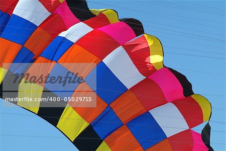 Detail of very large kite in various colours. Kite lines visible.