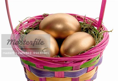 Colorful Easter basket containing 3 golden eggs.