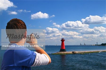 man with a compact camera taking a photo of a lighthouse