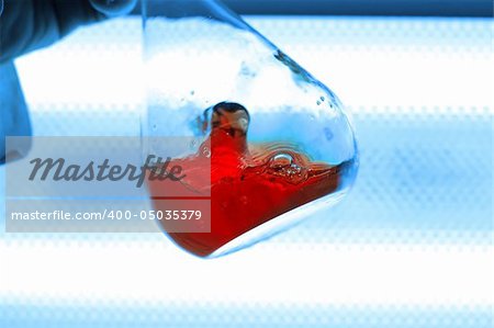 chemical retort with red liquid, white and blue background