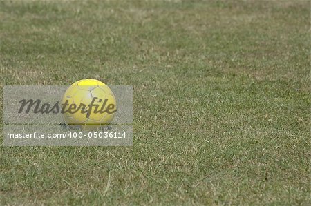 Yellow football on green grass.