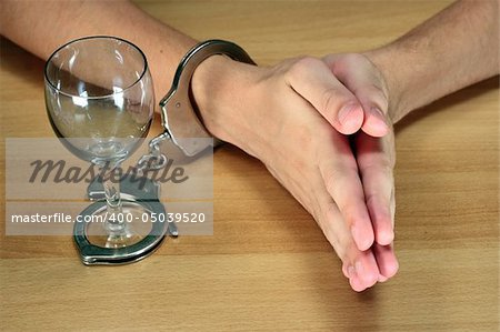 alcohol addiction, hands handcuffed with an epmty alcohol glass