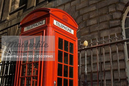 Classic bright red British telephone box set against ornate building