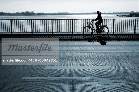 Female cyclist passing a bridge. Motion blur.