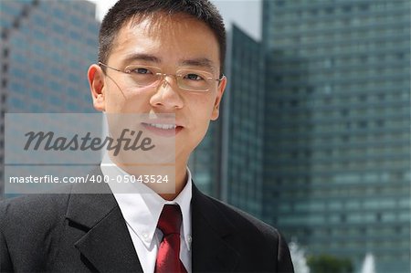 Young asian executive in front of modern office buildings.