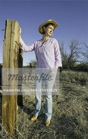Woman wearing a cowboy hat in a rural setting.