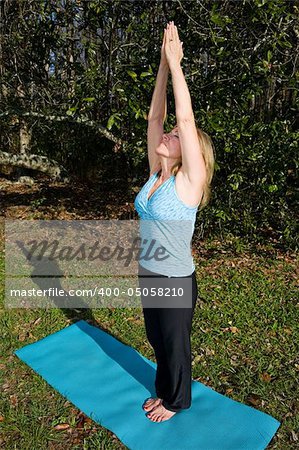 Beautiful sixty year old woman doing the yoga asana "salute to the sun" in a beautiful outdoor setting.