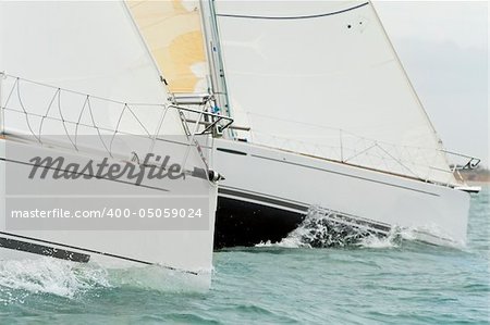 Close up on the bows of two racing yachts in close competition